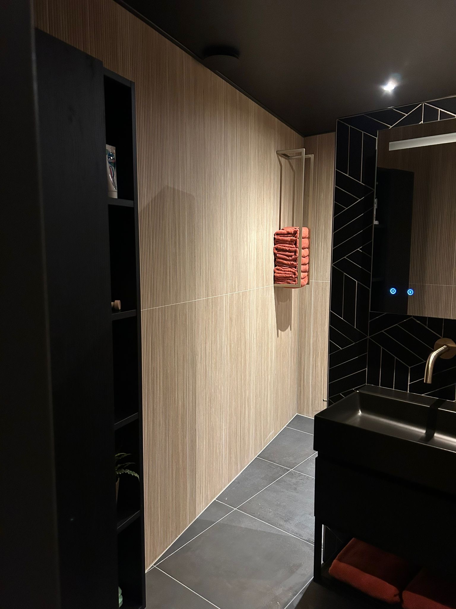 Donkere badkamer met houtlook wandtegels en zwarte visgraattegels