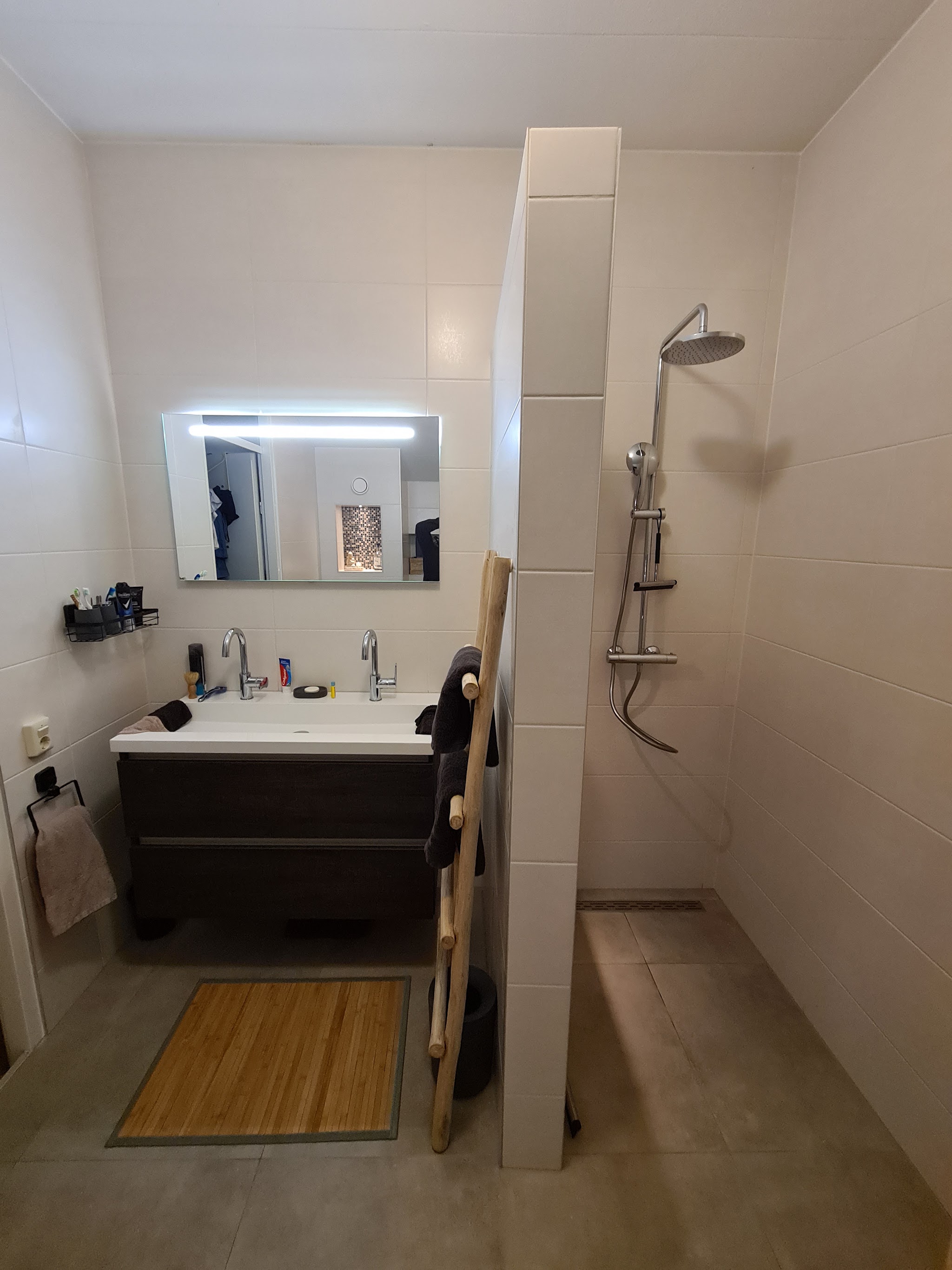 Witte badkamer met vrijstaande douchewand en verlicht spiegel